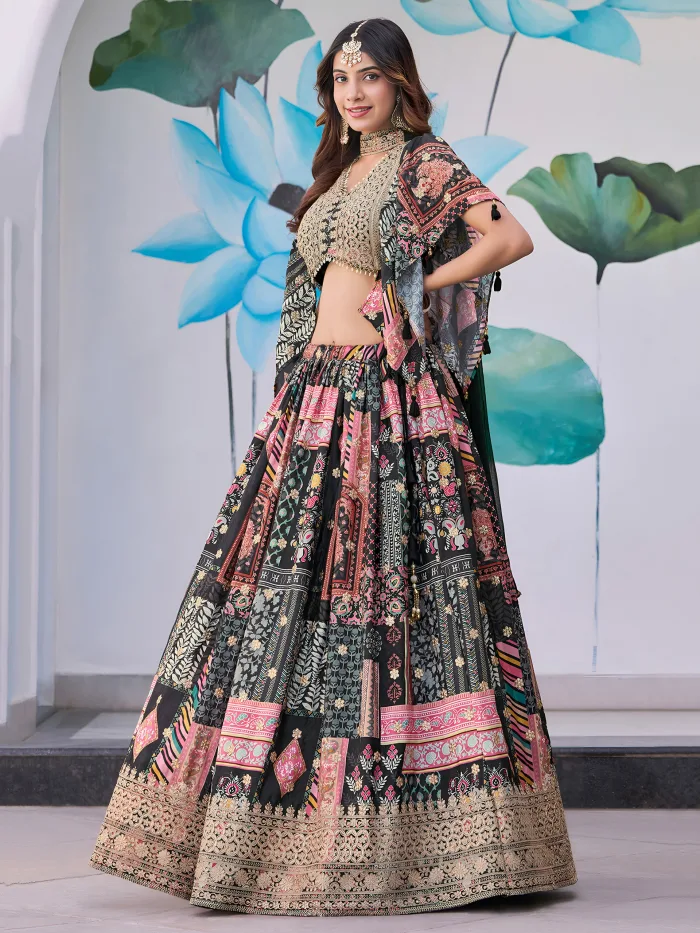 Woman wearing a black multicolor embroidered chinnon silk lehenga with cape sleeves and choker-style dupatta, perfect for weddings and festive occasions.