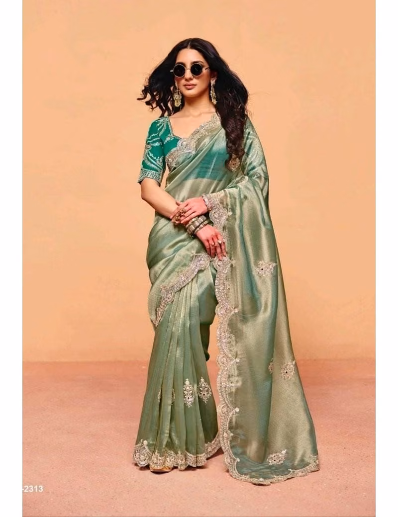 Model wearing a shimmering mint green pure fancy tissue designer saree with scalloped embroidered borders and a contrast dark green handwork blouse.