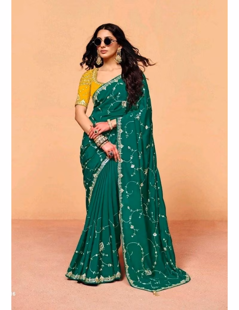 Model wearing a shimmering Emerald-Green pure fancy tissue designer saree with scalloped embroidered borders and a contrast maroon handwork blouse.