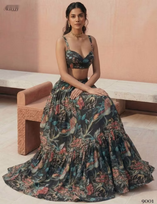 Model sitting on a stone bench wearing the Voguevive black floral print georgette lehenga, displaying the 4-meter skirt flare.