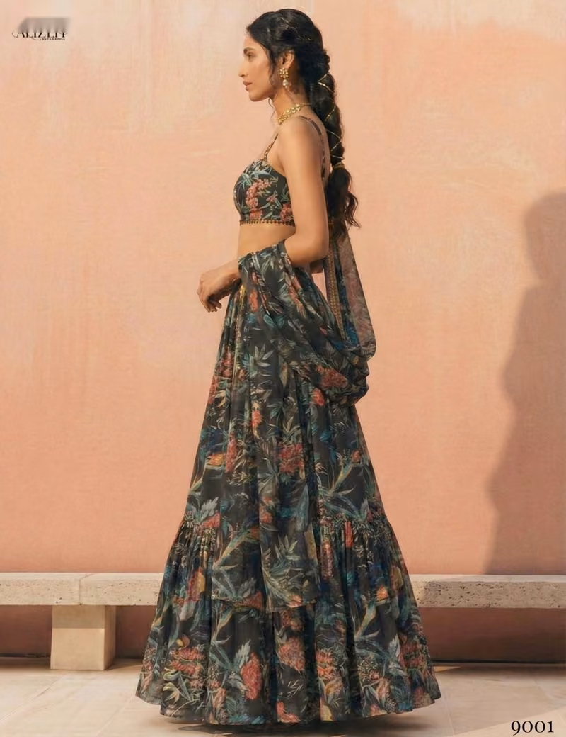 Woman modeling a Voguevive black floral print georgette lehenga choli with a matching draped dupatta, showing the side profile and skirt flare.