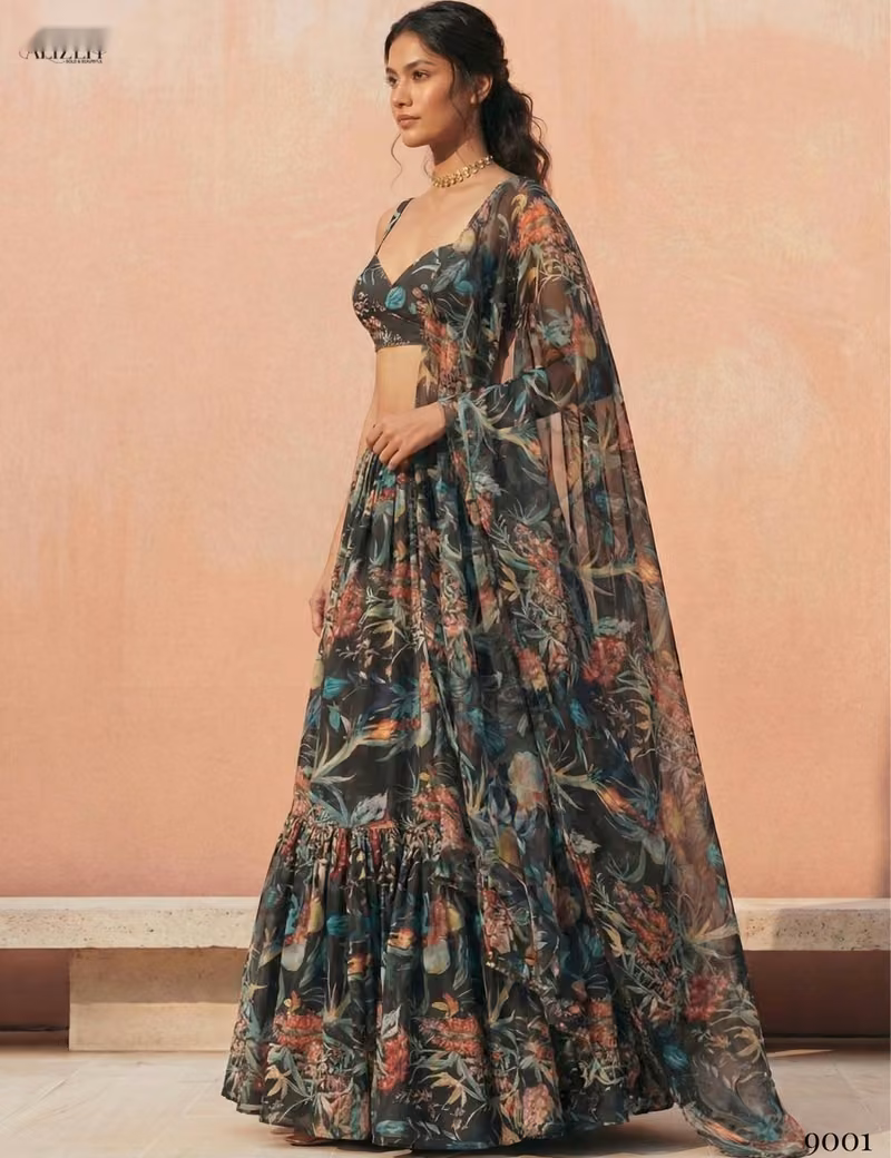 Woman modeling a Voguevive black floral print georgette lehenga choli with a matching draped dupatta, showing the side profile and skirt flare.