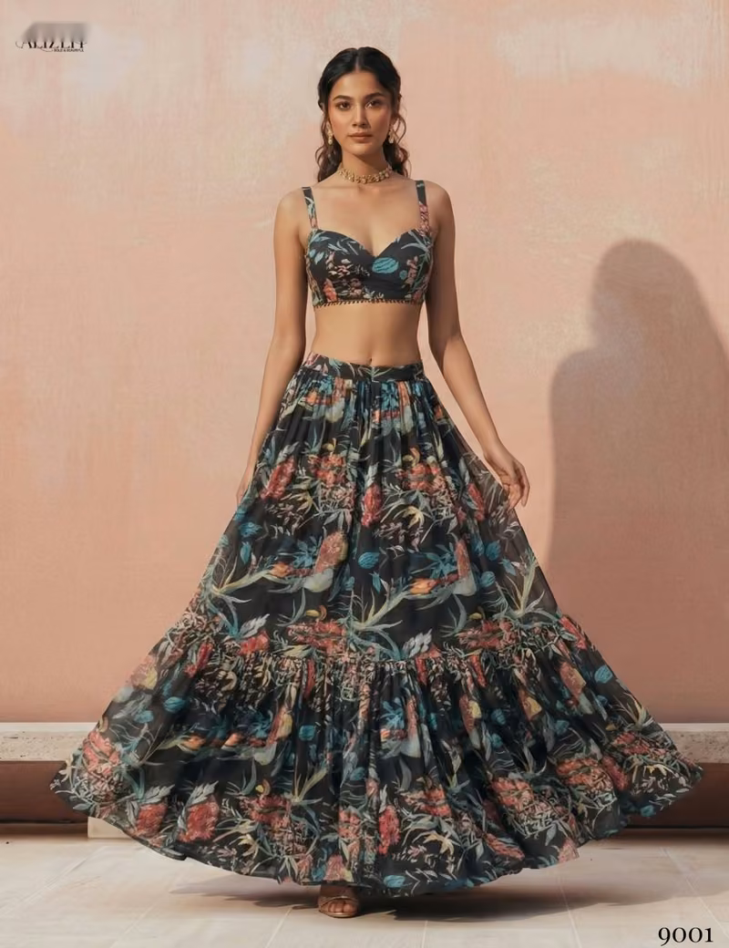 Front view of a woman wearing a black sleeveless crop top and a tiered floral print georgette lehenga skirt by Voguevive.